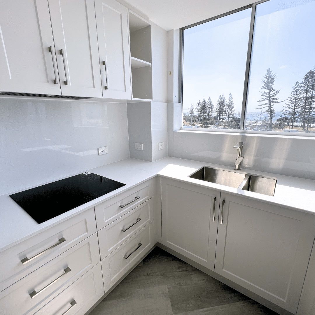 A Kitchen With White Cabinets And A Black Stove Top — Nyblad Construction in Caloundra West, QLD