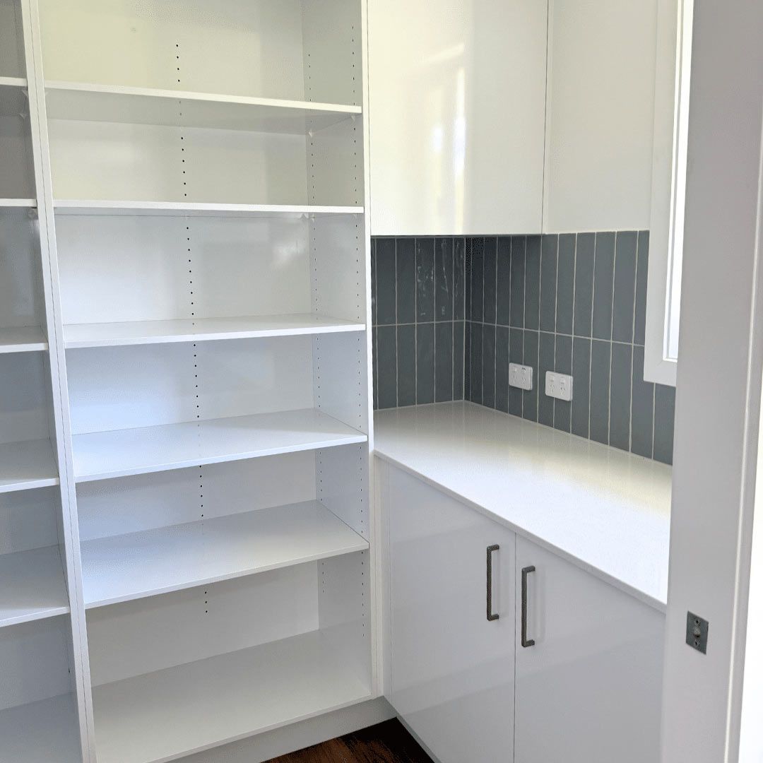 A Bright Kitchen With White Cabinets, Open Shelves, And A Window — Nyblad Construction in Caloundra West, QLD