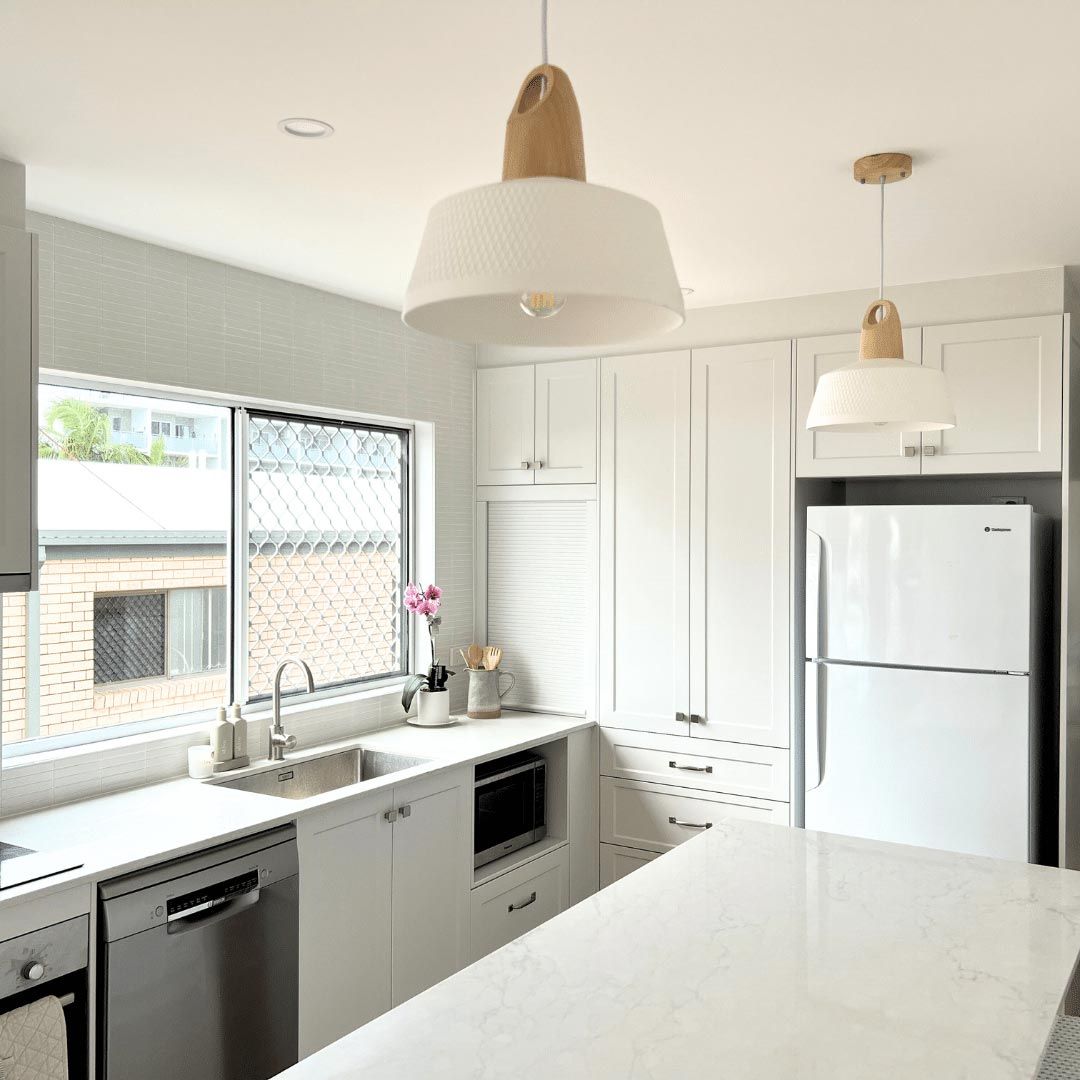 A Kitchen With White Cabinets And A White Refrigerator And Two Ceiling Lamps — Nyblad Construction in Caloundra West, QLD
