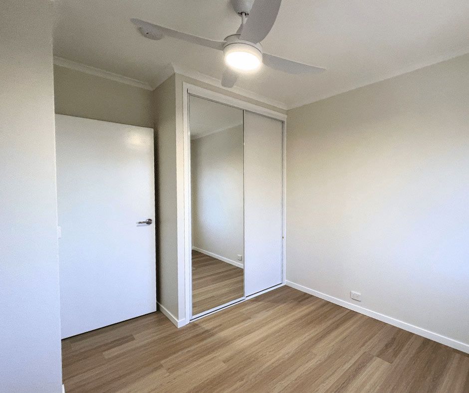 A Bedroom With A Ceiling Fan And A Mirrored Wardrobe — Nyblad Construction in Caloundra West, QLD
