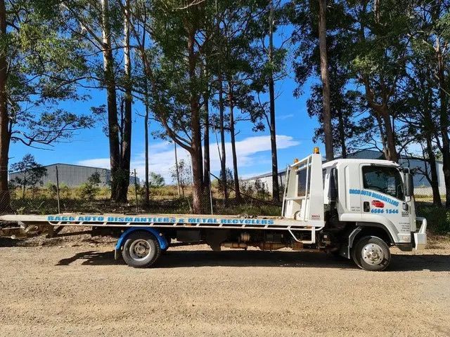 A White Tow Truck With A Flat Bed Is Parked In Front Of Trees — Bago Auto Dismantlers in Wauchope, NSW