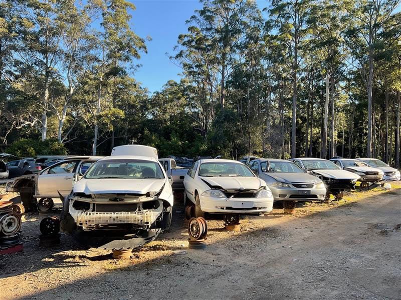 A Row Of Cars Are Sitting On The Side Of The Road In A Junkyard — Bago Auto Dismantlers in Laurieton, NSW
