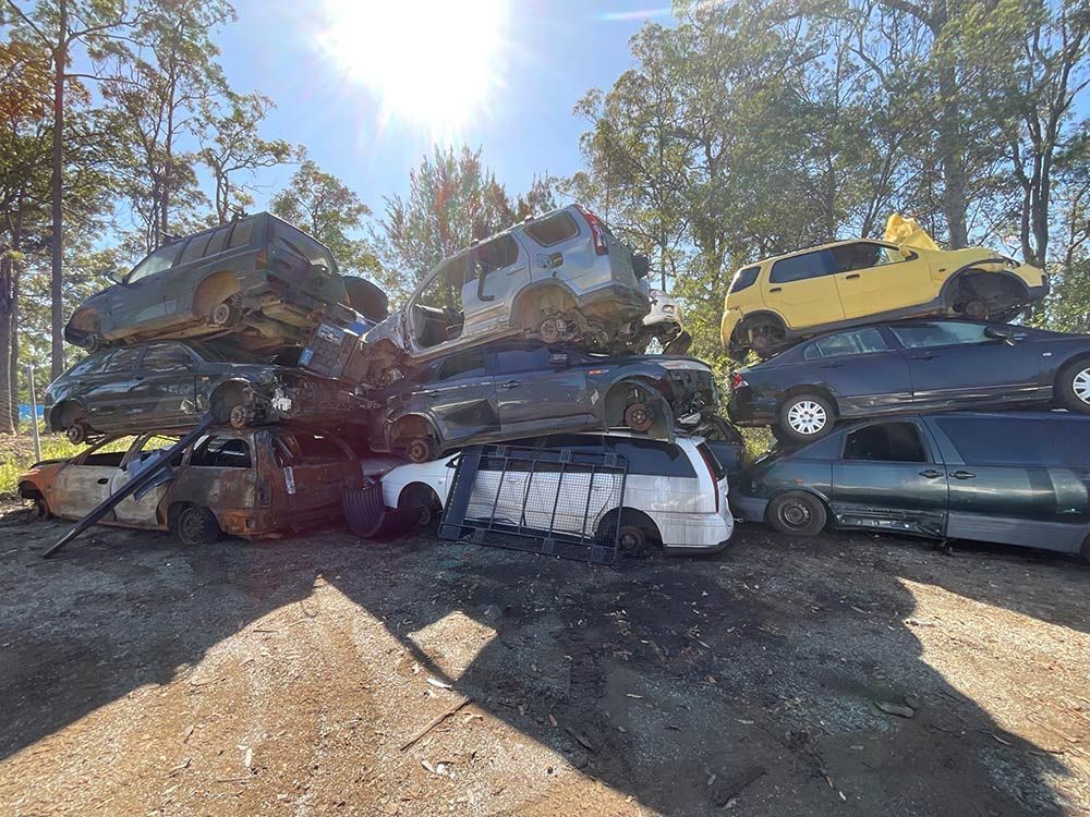 A Bunch Of Cars Are Stacked On Top Of Each Other In A Scrap Yard — Bago Auto Dismantlers in Wauchope, NSW