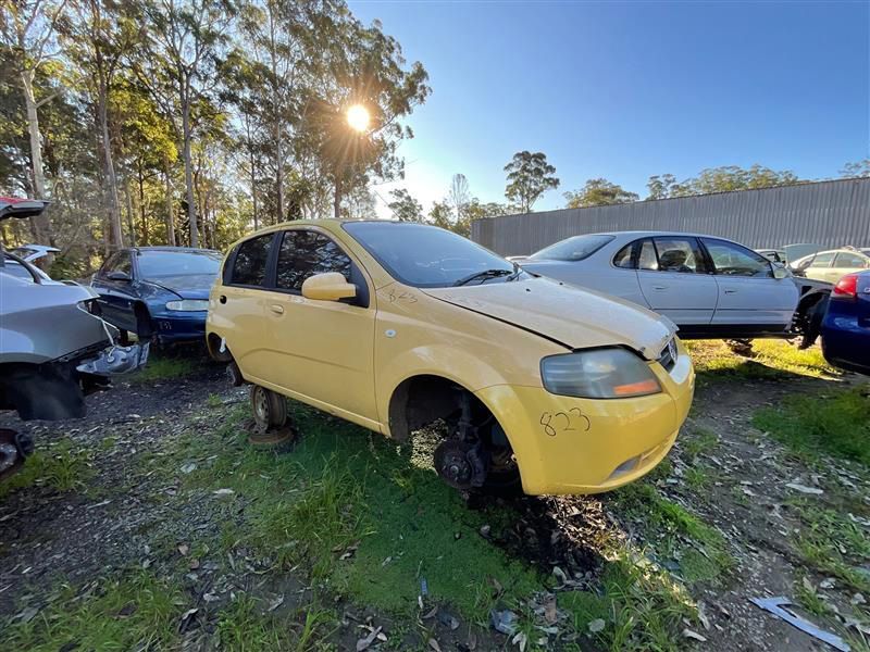 A Yellow Car Is Sitting In A Grassy Field Next To Other Cars — Bago Auto Dismantlers in Wauchope, NSW