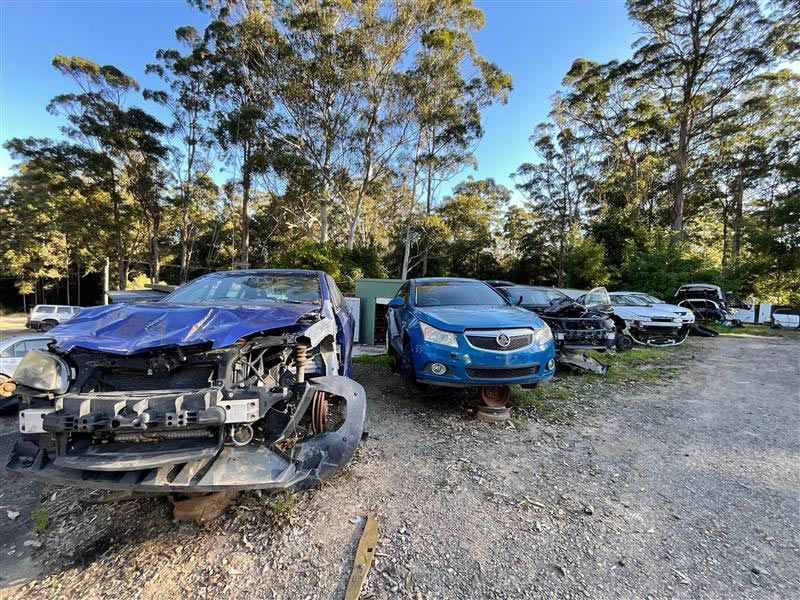 A Row of Wrecked Cars Are Parked in a Gravel Lot — Bago Auto Dismantlers in Bonny Hills, NSW