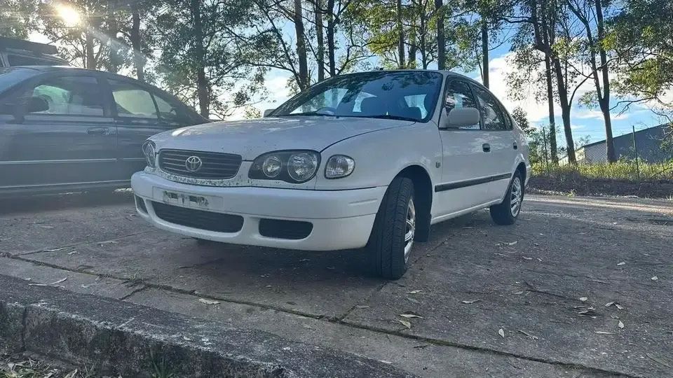 A White Toyota Corolla Is Parked On The Side Of The Road — Bago Auto Dismantlers in Wauchope, NSW