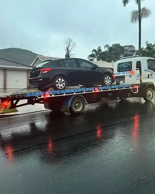 A Tow Truck Is Towing A Car On A Flatbed Trailer — Bago Auto Dismantlers in Wauchope, NSW
