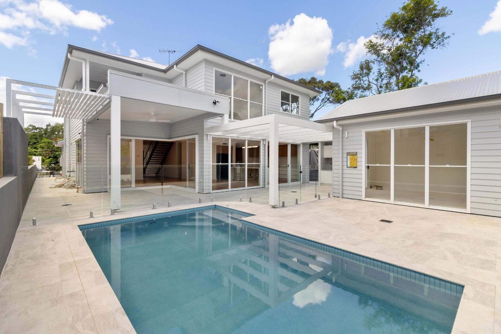 Modern white house with a backyard pool and patio, viewed from the courtyard