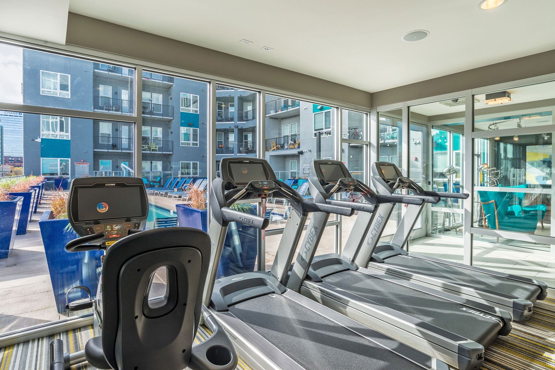 Indoor fitness center with treadmills and large windows overlooking the pool.