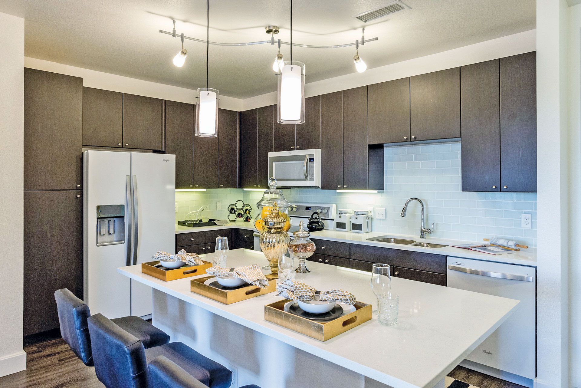 Modern kitchen with dark wood cabinets, white countertops, stainless appliances, and an island with seating.