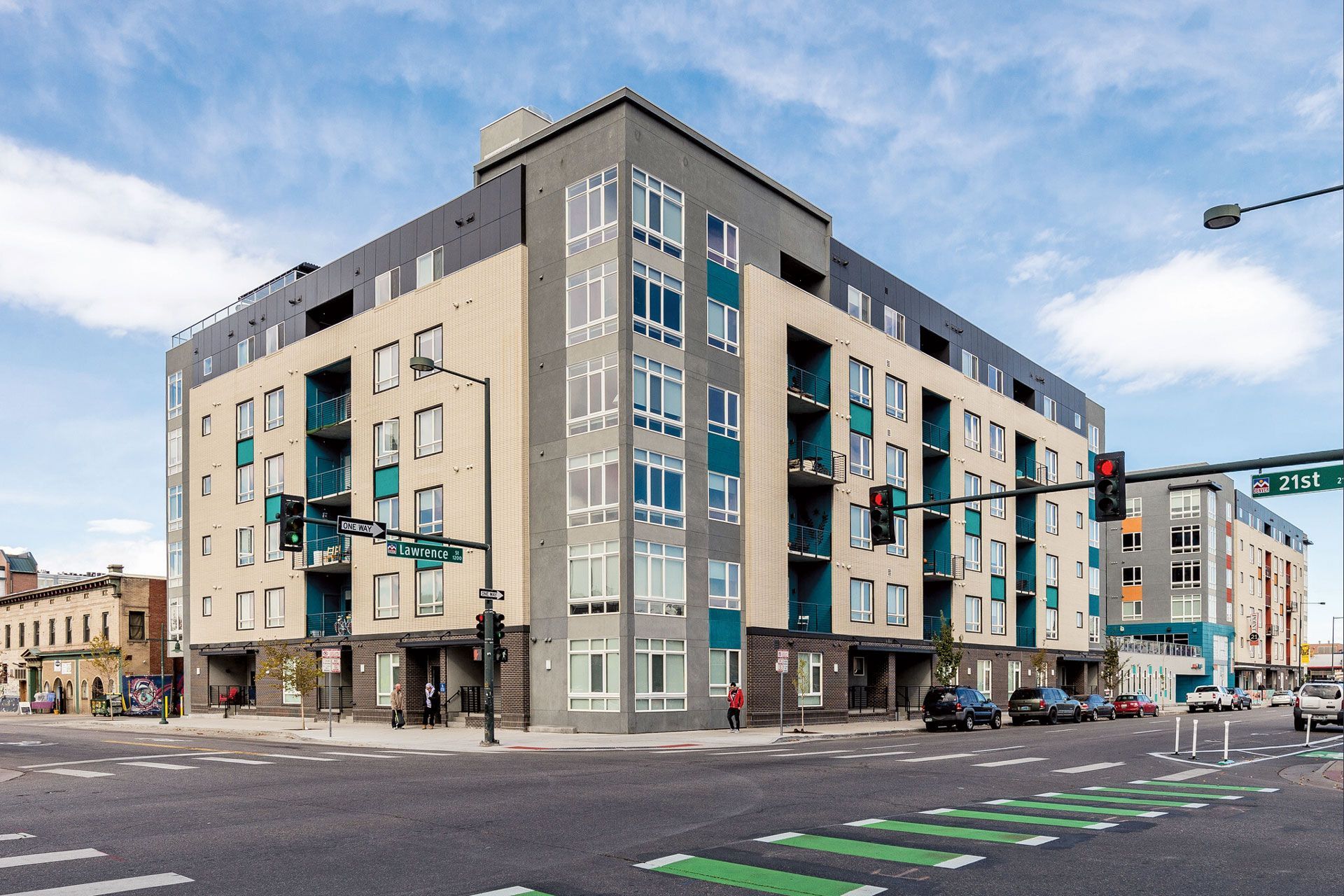 Exterior view of a modern multi-story apartment building at a busy street corner.