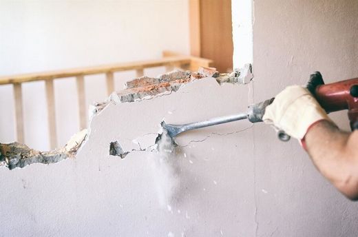 A person is breaking a wall with a hammer.