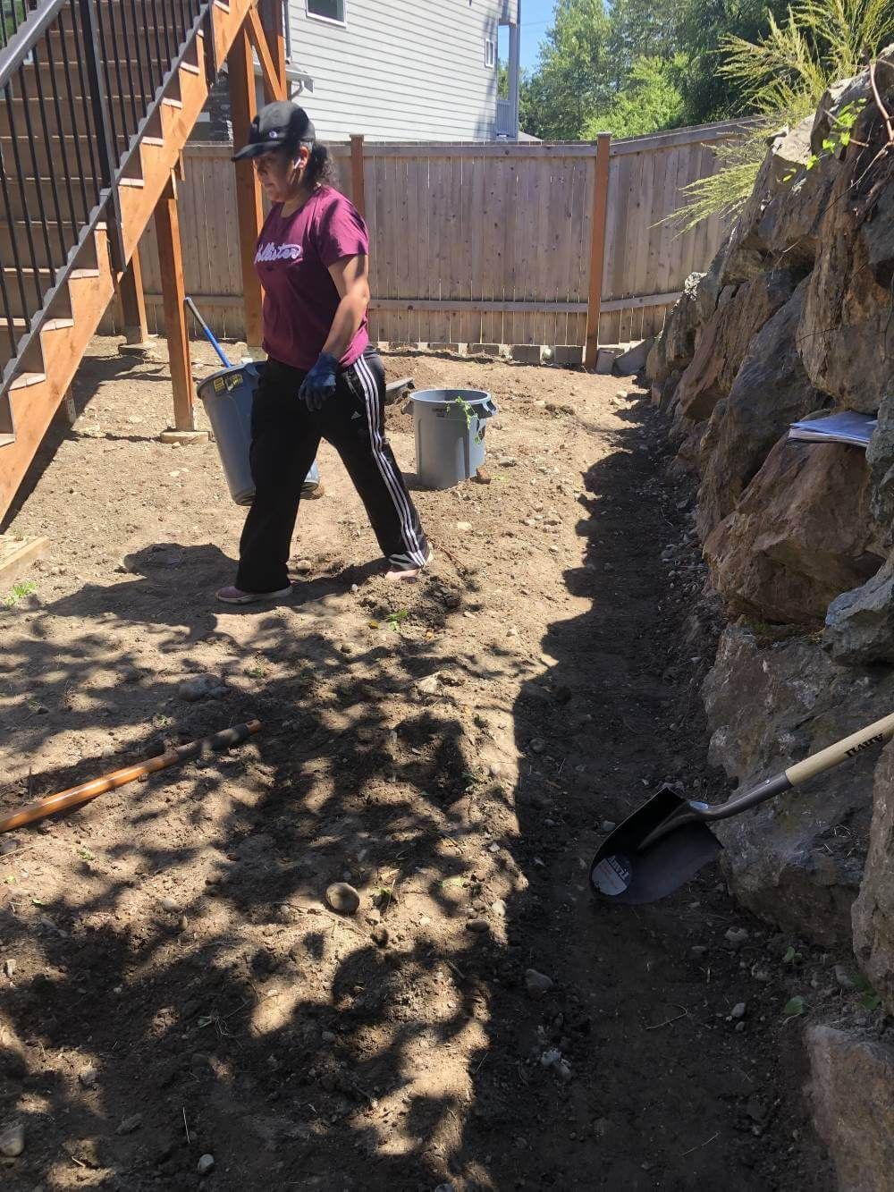 A woman is digging in the dirt with a shovel and bucket.