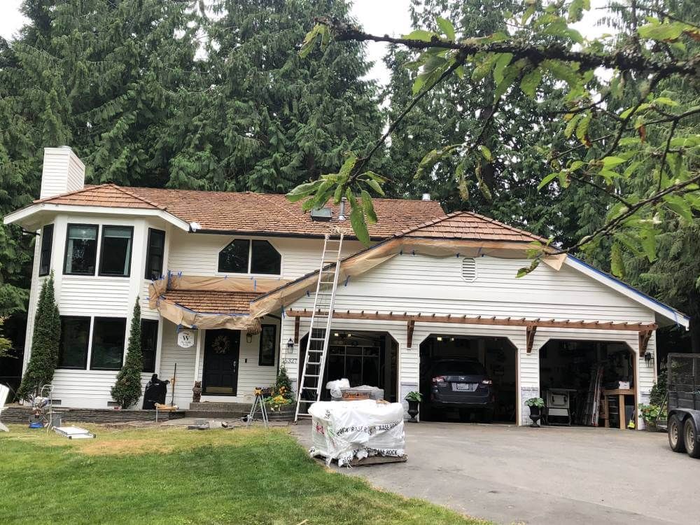 A large white house with a brown roof is being remodeled.