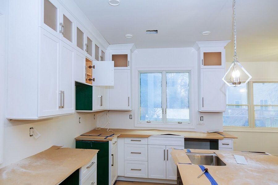 A kitchen under construction with white cabinets and a sink.