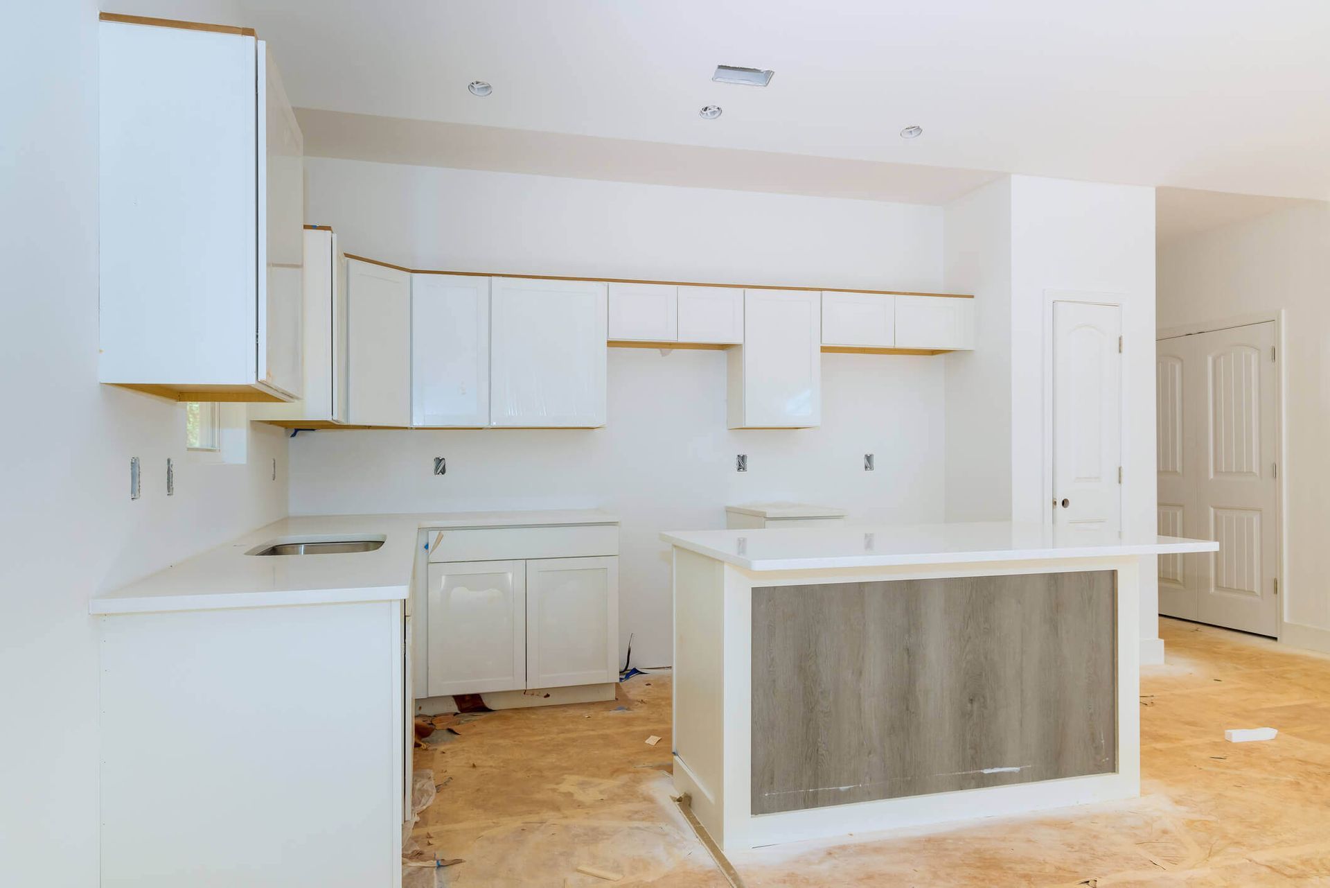 A kitchen under construction with white cabinets and a wooden island.