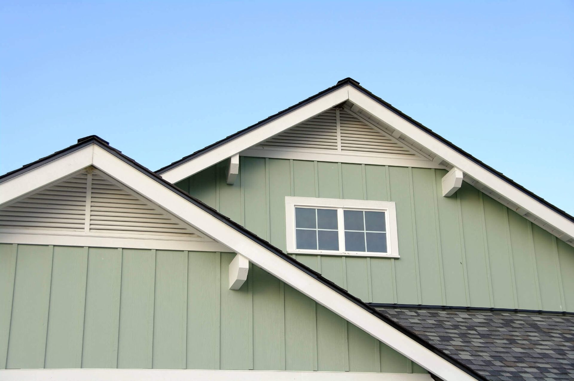 A green house with a white trim and a black roof