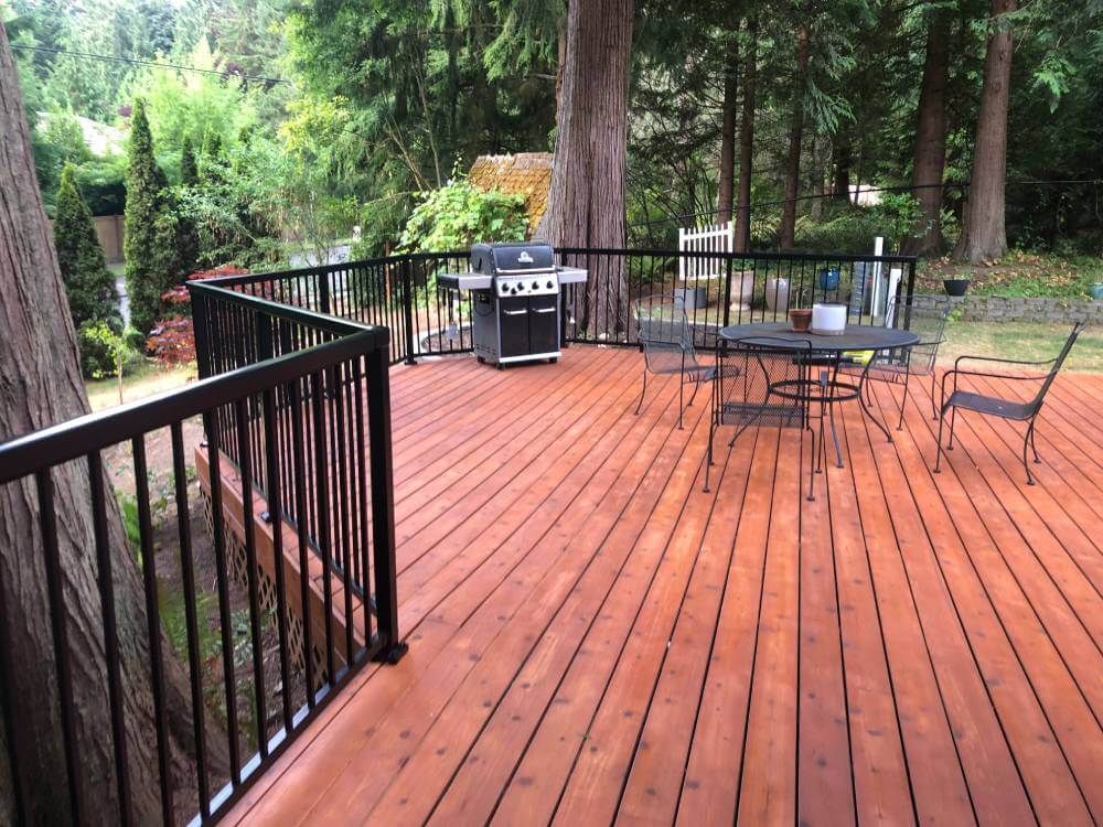 A wooden deck with a table and chairs and a grill.