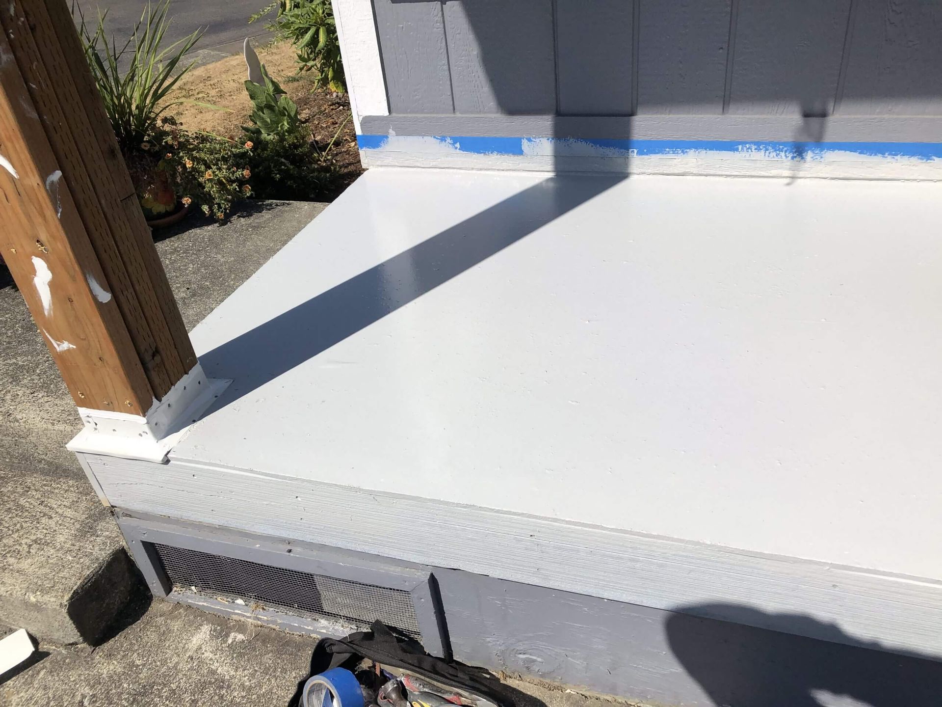 A white porch is being painted on a house.