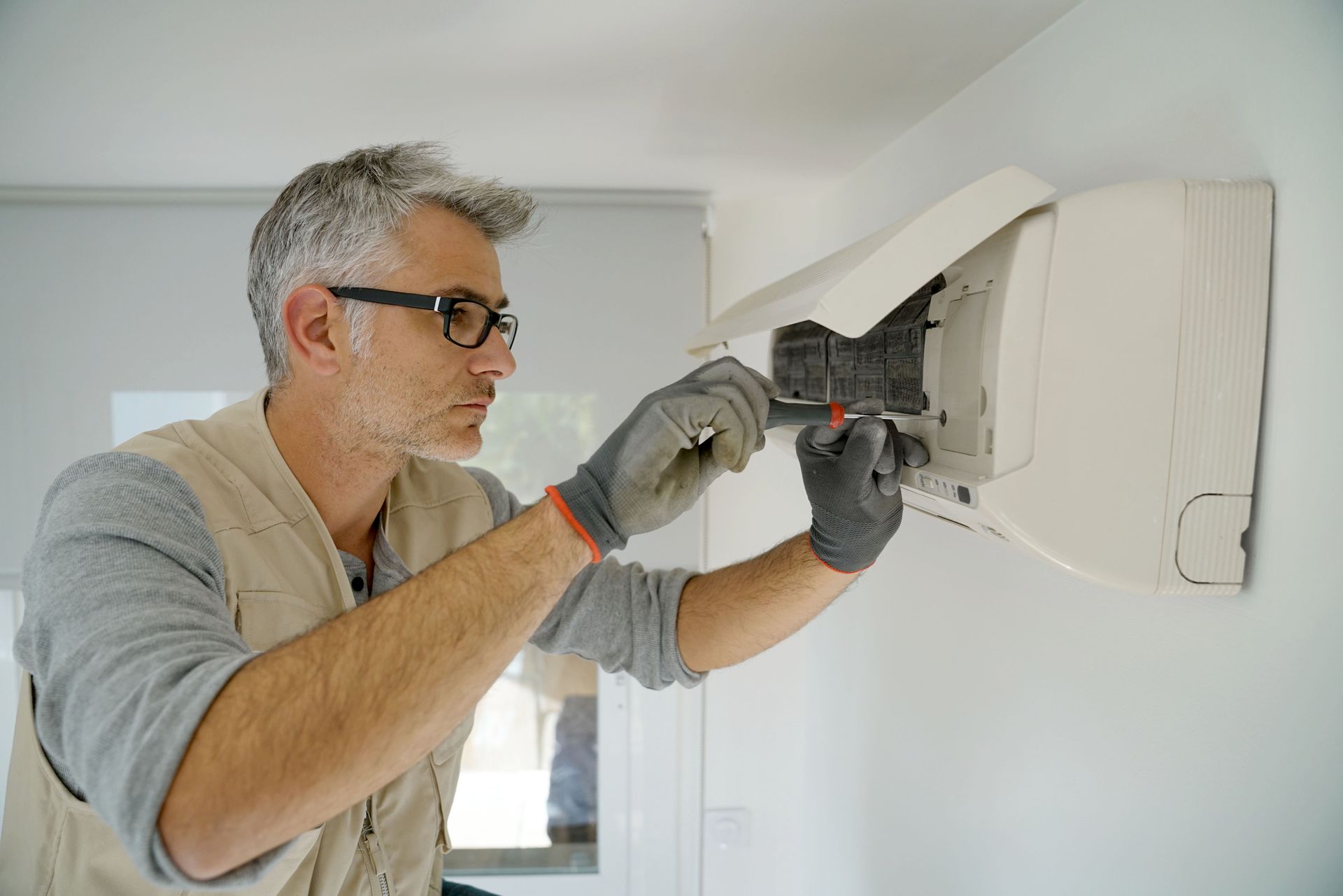 An experienced repairman diligently working on fixing an air conditioner unit, focused on diagnosing and repairing the internal components to restore optimal cooling functionality