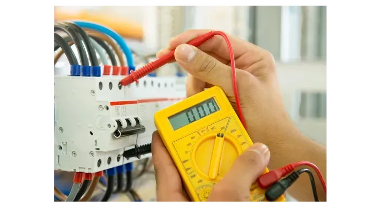 Une personne utilise un multimètre numérique pour tester un circuit imprimé.