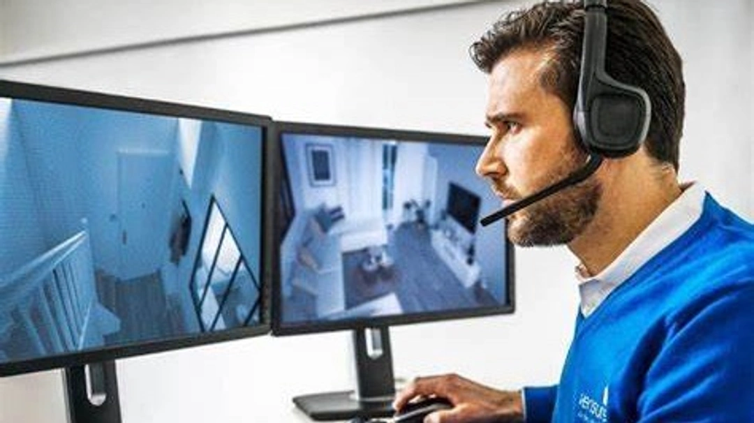 Un homme portant des écouteurs est assis devant deux écrans d'ordinateur.