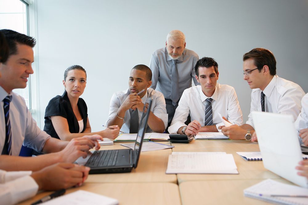 Un groupe de personnes sont assises autour d'une table avec des ordinateurs portables.