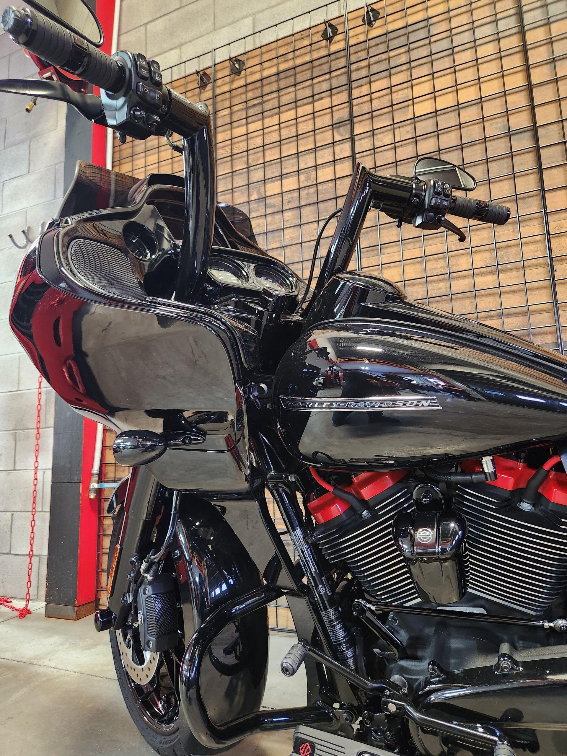 Moto Harley-Davidson noire avec guidon haut, accents rouges, sur fond texturé.