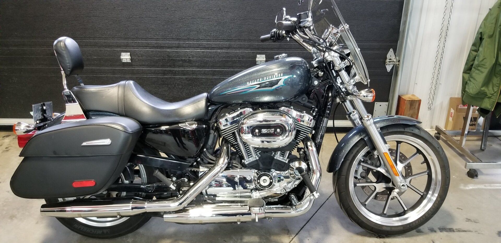 Une moto Harley-Davidson vert foncé avec des sacoches et un pare-brise garée à l'intérieur.