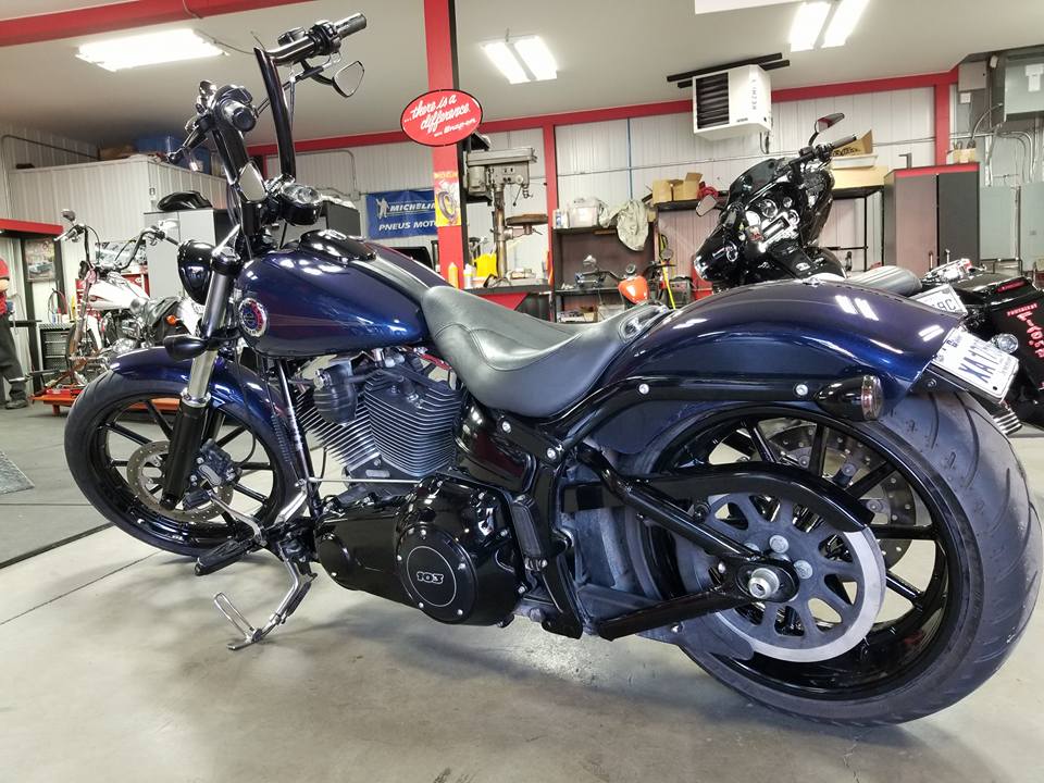 Moto Harley-Davidson bleu foncé dans un garage, pièces noires, guidon haut.