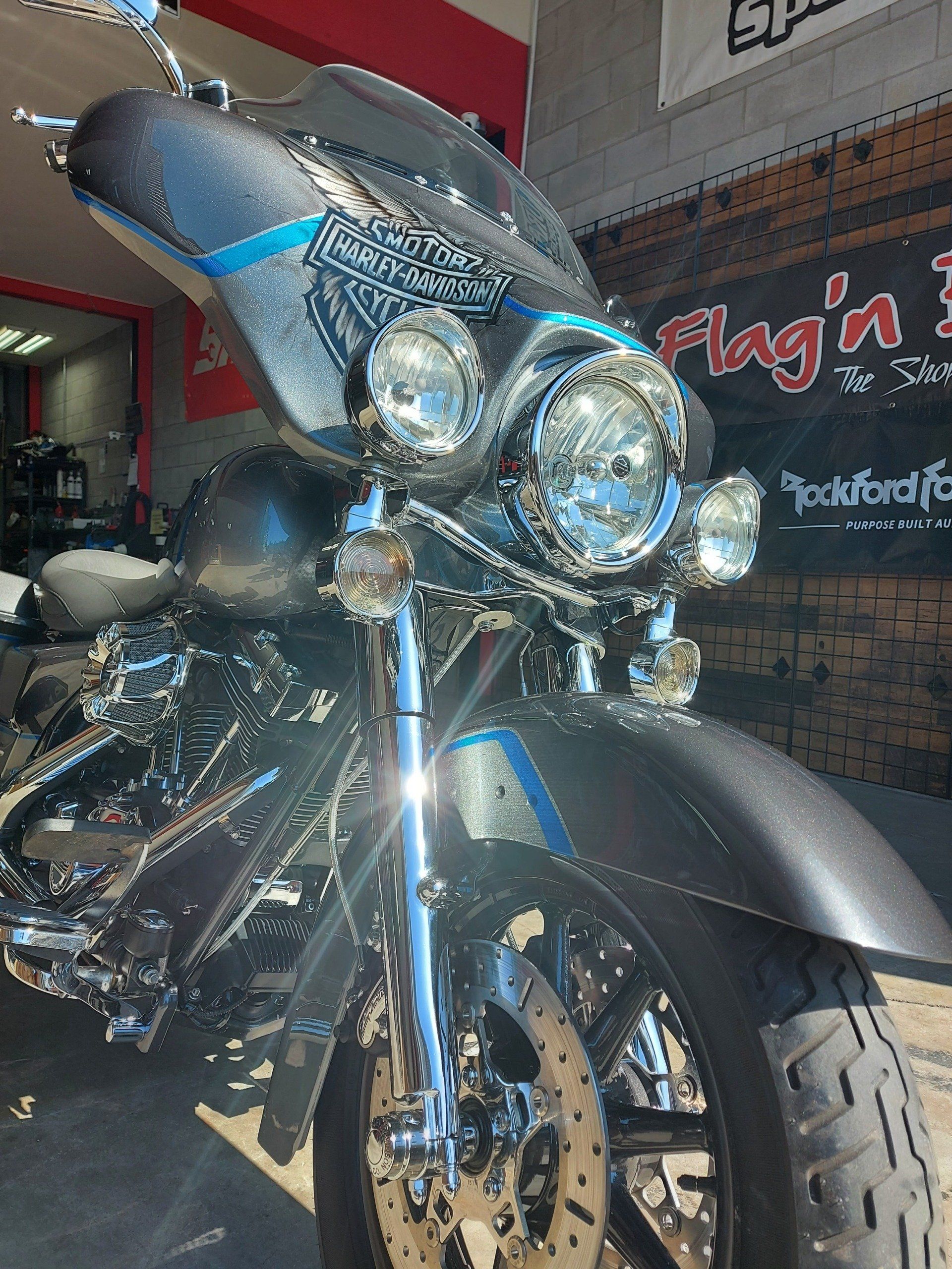 Moto Harley Davidson noire et chromée avec des accents bleus, garée à l'intérieur.