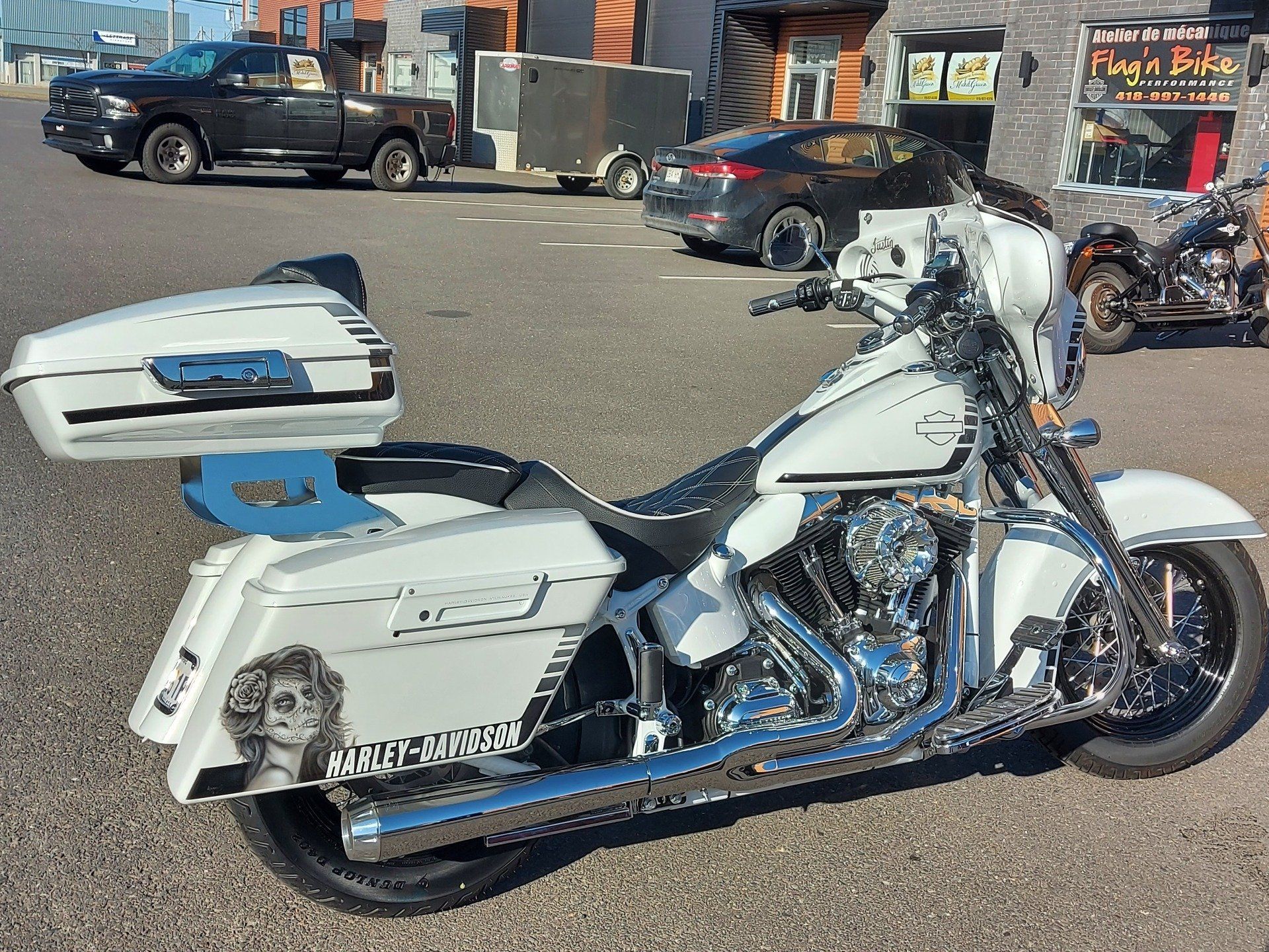 Moto Harley-Davidson blanche garée à l'extérieur, présentant des détails personnalisés, notamment un graphique latéral représentant une femme.