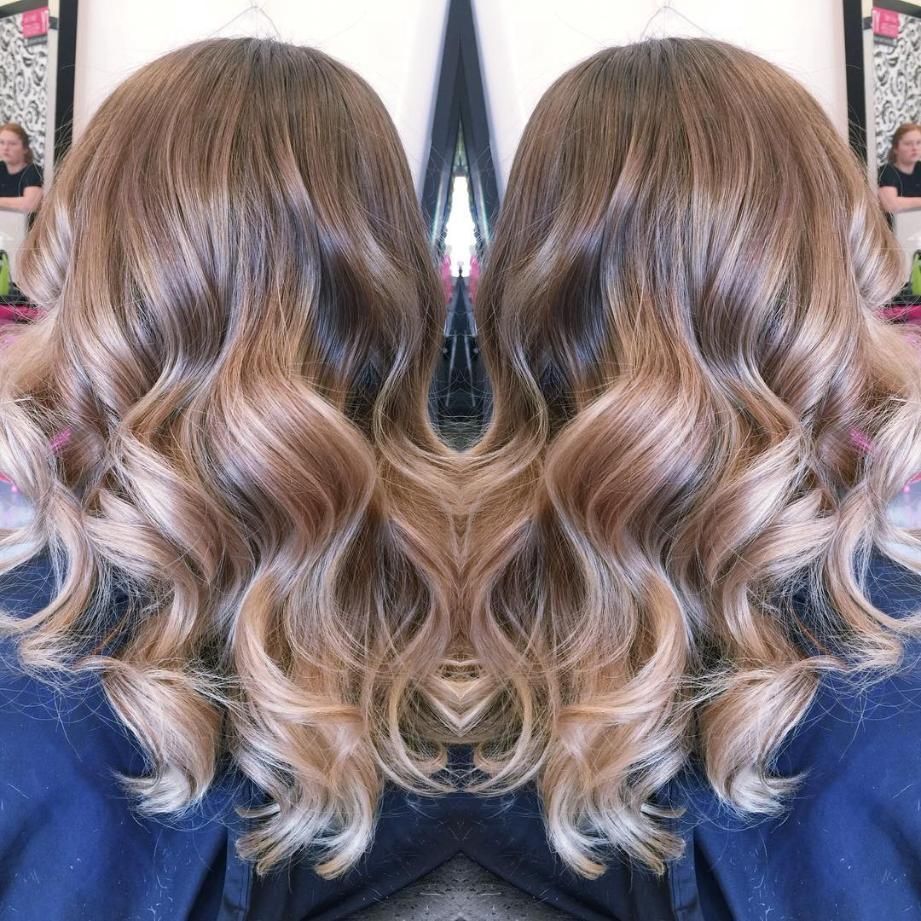 A Woman With Long Wavy Hair is Standing in Front of a Mirror — Choo Choo Hair and Beauty In Wyong, NSW