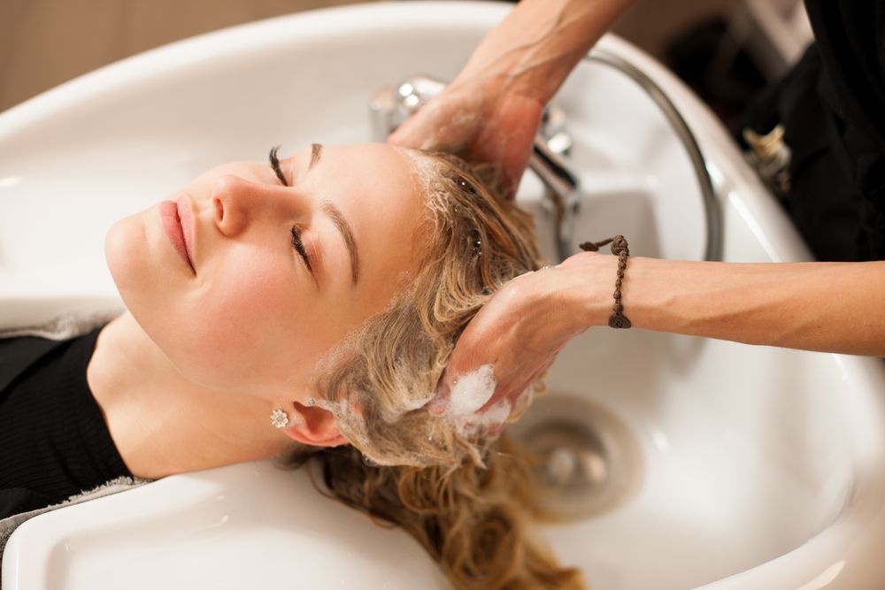 A Woman is Getting Her Hair Washed in a Sink at a Salon — Choo Choo Hair and Beauty In Wyong, NSW