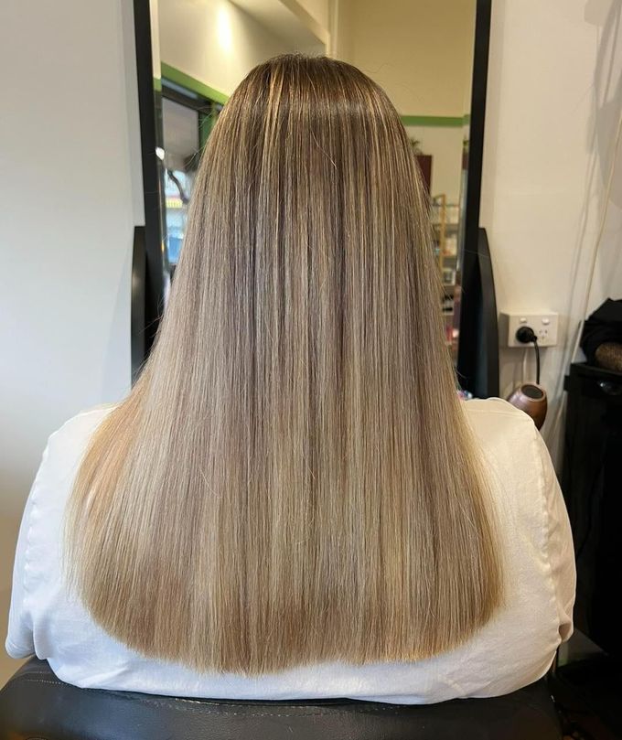 A Woman With Long Blonde Hair is Sitting in a Chair in Front of a Mirror — Elysian Salon In Wyong, NSW