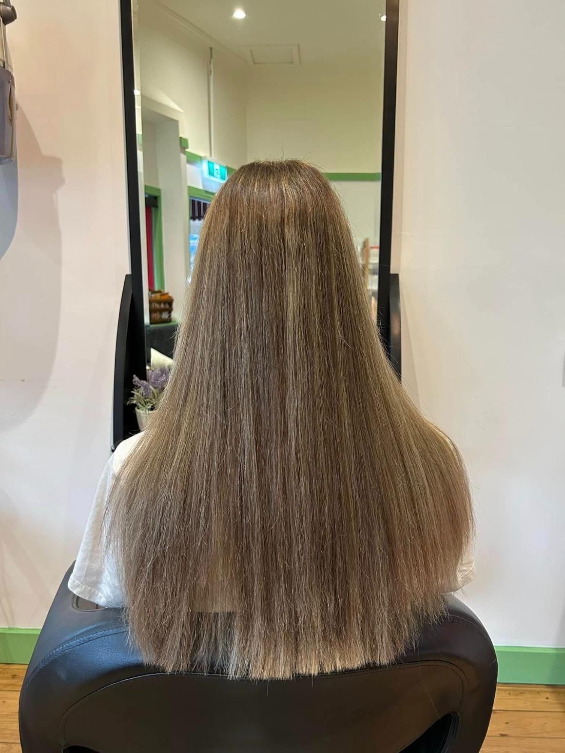 A Woman With Long Hair is Sitting in a Chair in Front of a Mirror — Choo Choo Hair and Beauty In Wyong, NSW