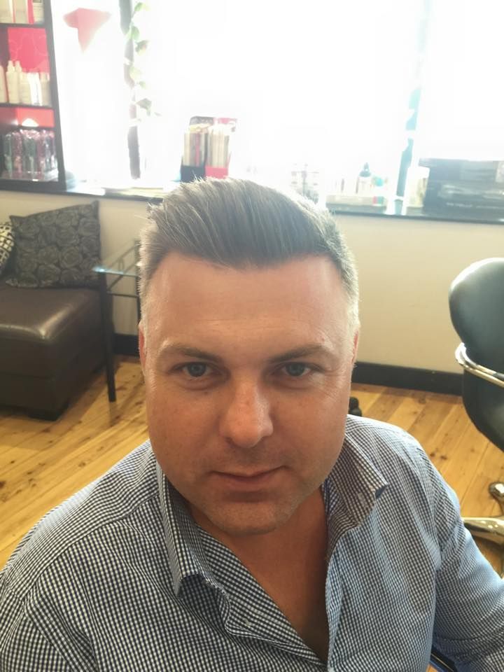 A Man in a Blue Shirt is Sitting in a Chair in a Salon — Choo Choo Hair and Beauty In Wyong, NSW