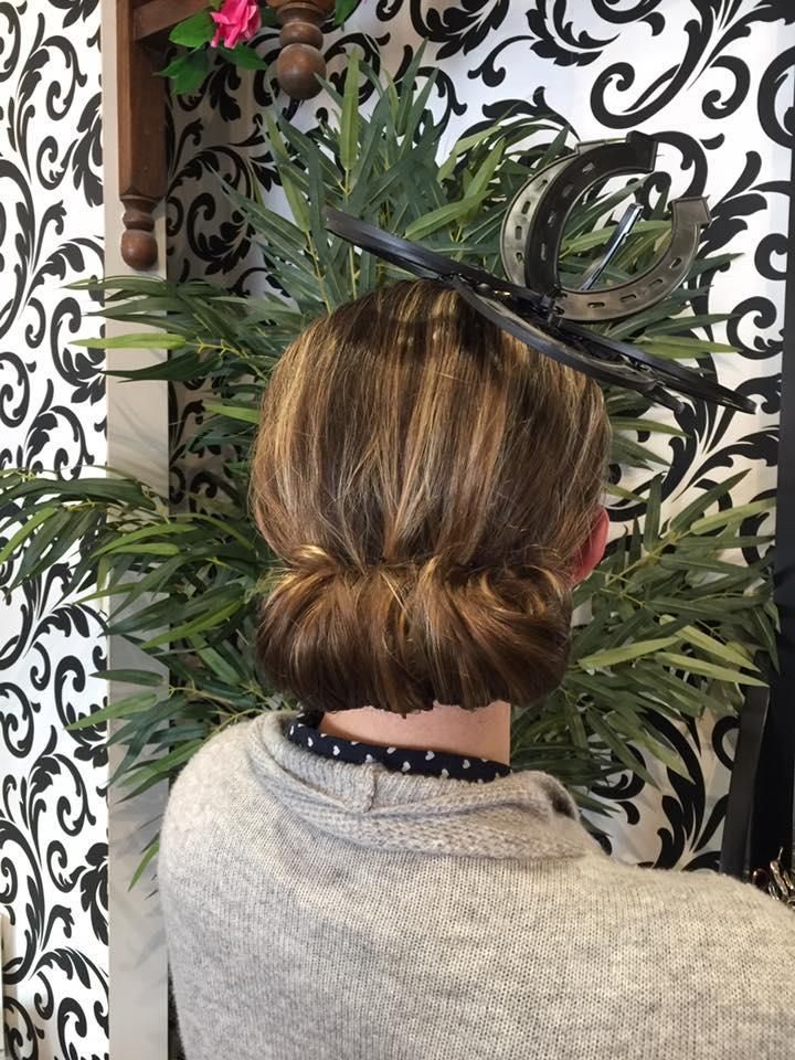 A Woman Wearing a Hat and a Bun is Standing in Front of a Plant — Choo Choo Hair and Beauty In Wyong, NSW