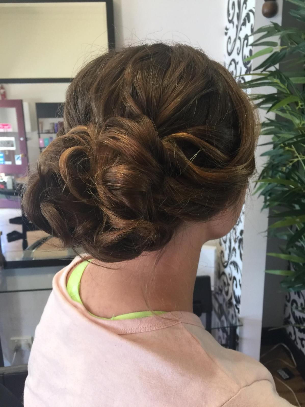 A Woman With Her Hair in a Bun is Sitting in Front of a Mirror — Choo Choo Hair and Beauty In Wyong, NSW
