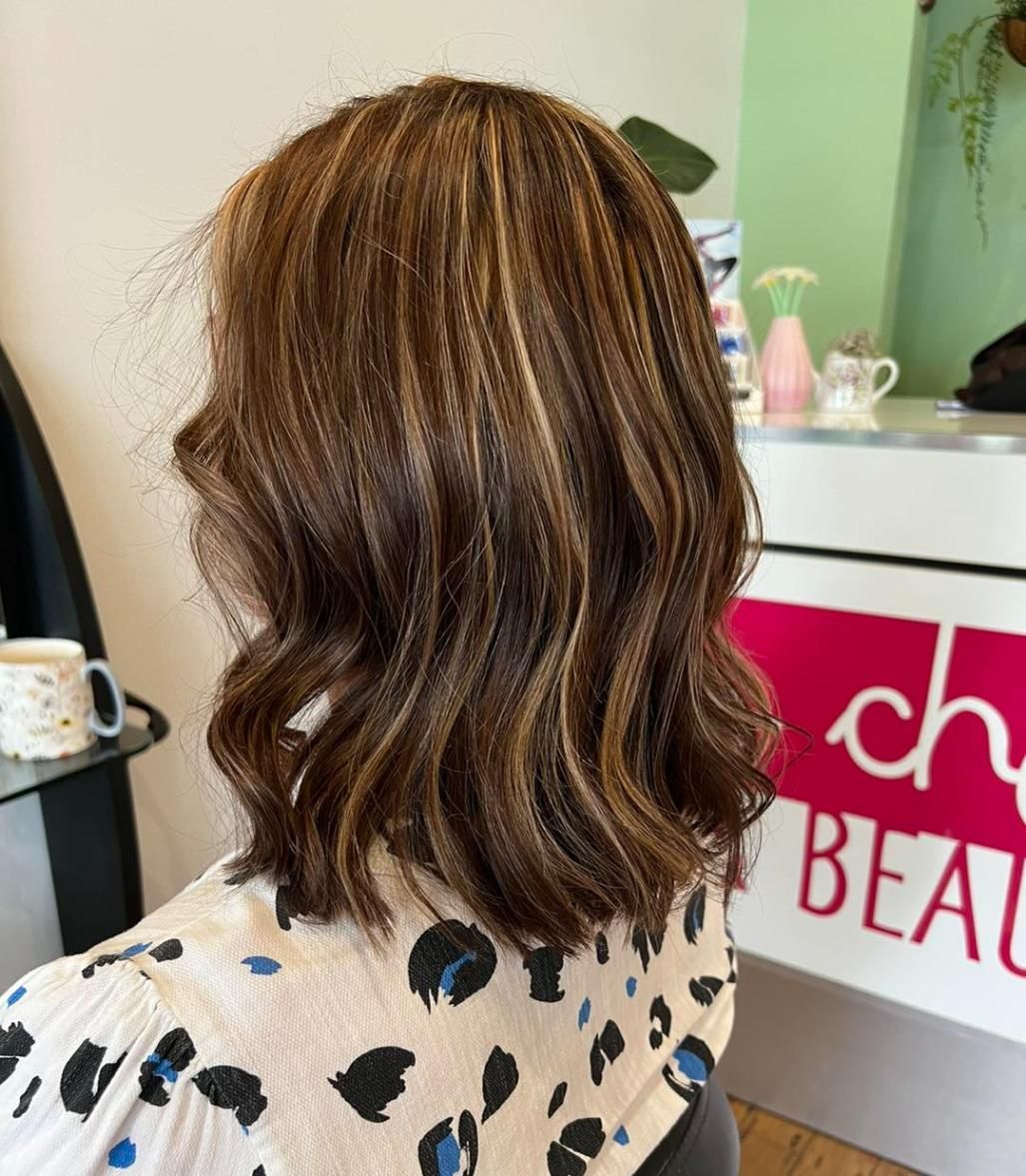 A Woman is Sitting in a Chair in Front of a Sign That Says Cherry Bears — Choo Choo Hair and Beauty In Wyong, NSW