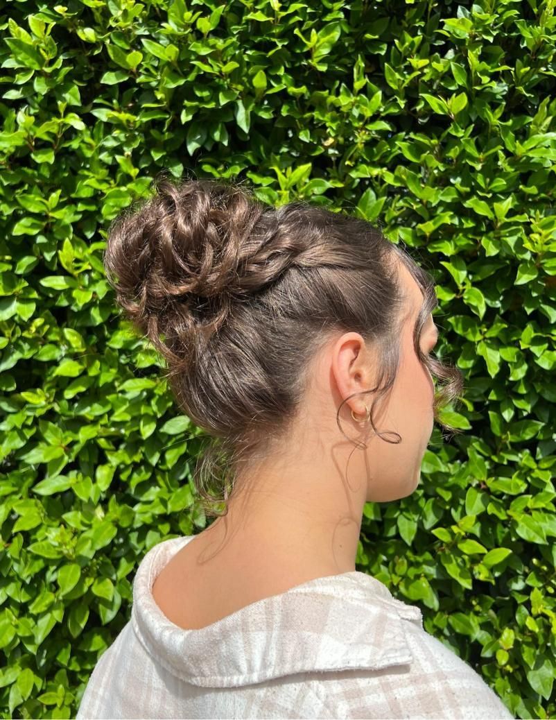 A Woman With Her Hair in a Bun is Standing in Front of a Bush — Choo Choo Hair and Beauty In Wyong, NSW