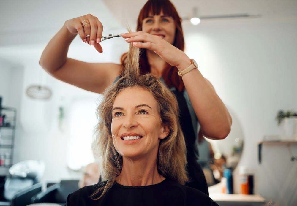 Stylist Cutting a Smiling Customer’s Hair in a Bright Salon — Elysian Salon In Wyong, NSW
