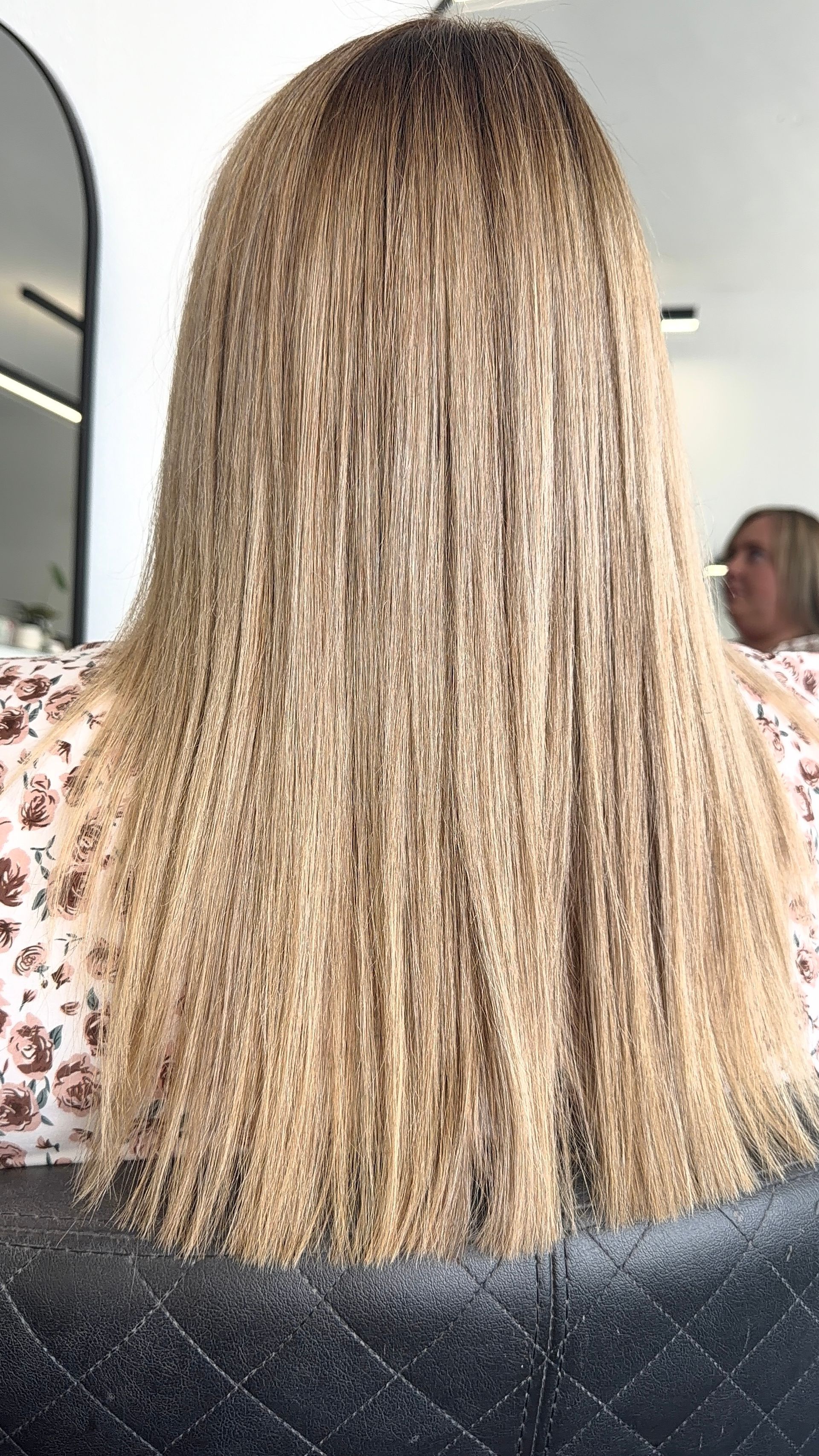 Back view of shoulder-length, highlighted wavy hair in a salon chair — Elysian Salon In Wyong, NSW