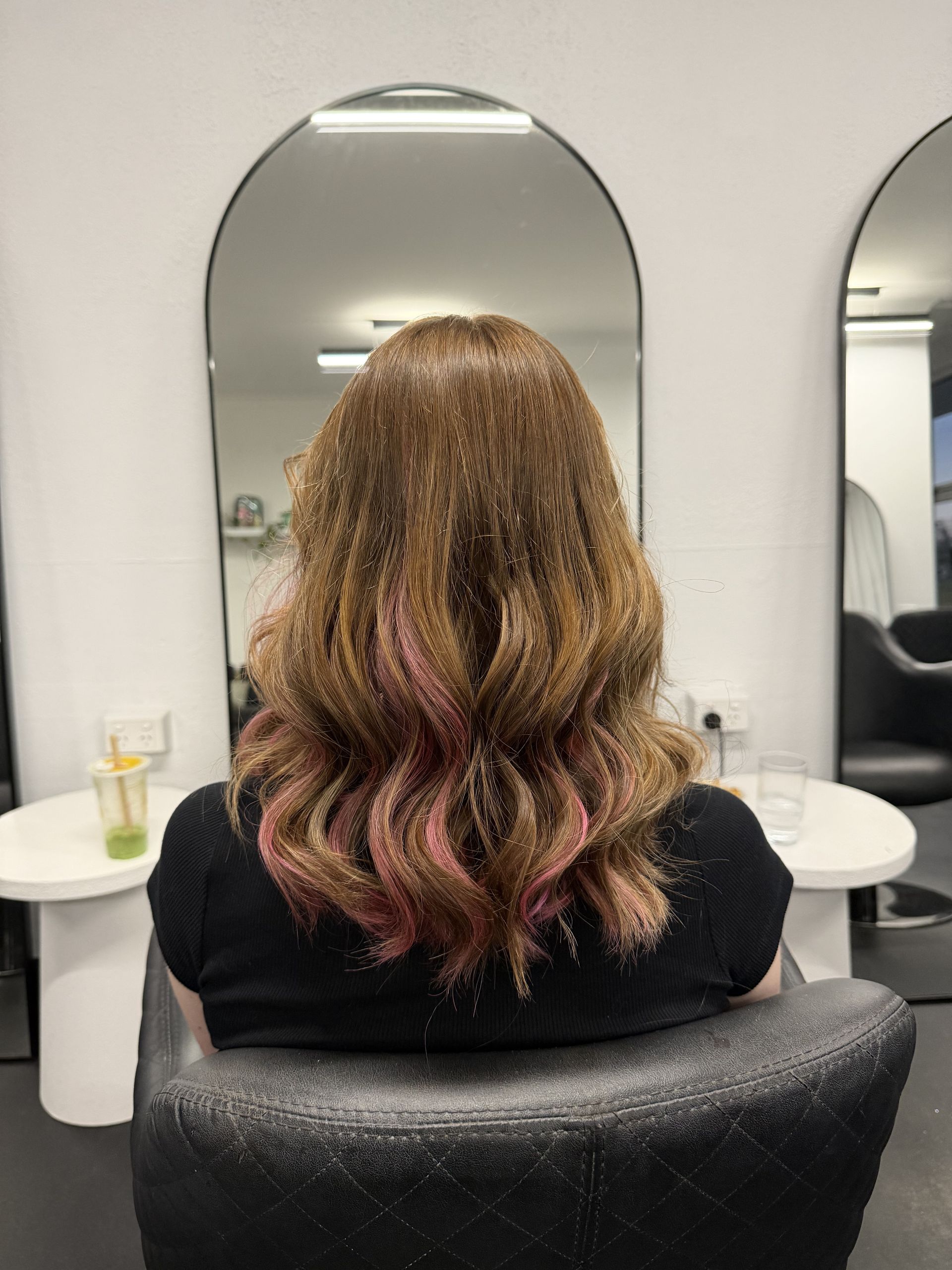 Person with long wavy brown hair and pink tips seated in a salon chair, seen from behind  — Elysian Salon In Wyong, NSW