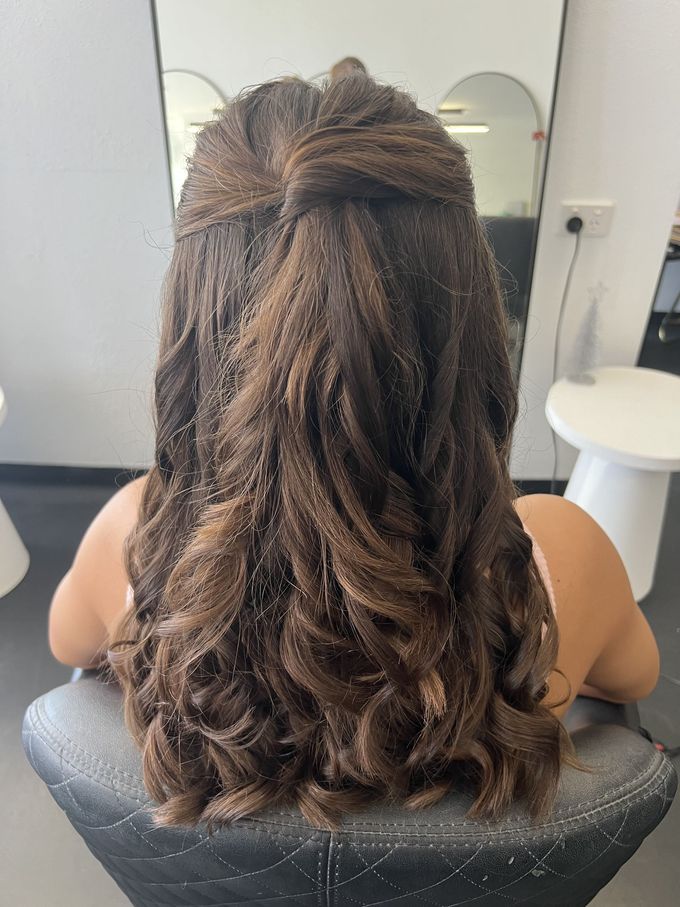 Back view of a person with long wavy brown hair in a salon chair, facing a mirror — Elysian Salon In Wyong, NSW