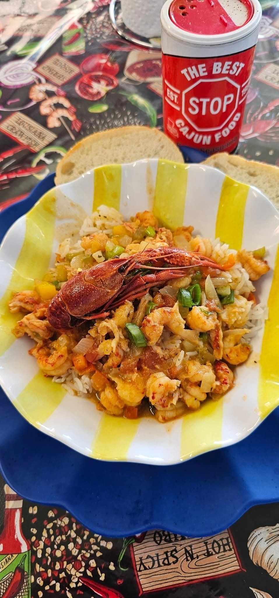 Shrimp jambalaya with bread and a coffee cup, on a plate with yellow stripes.