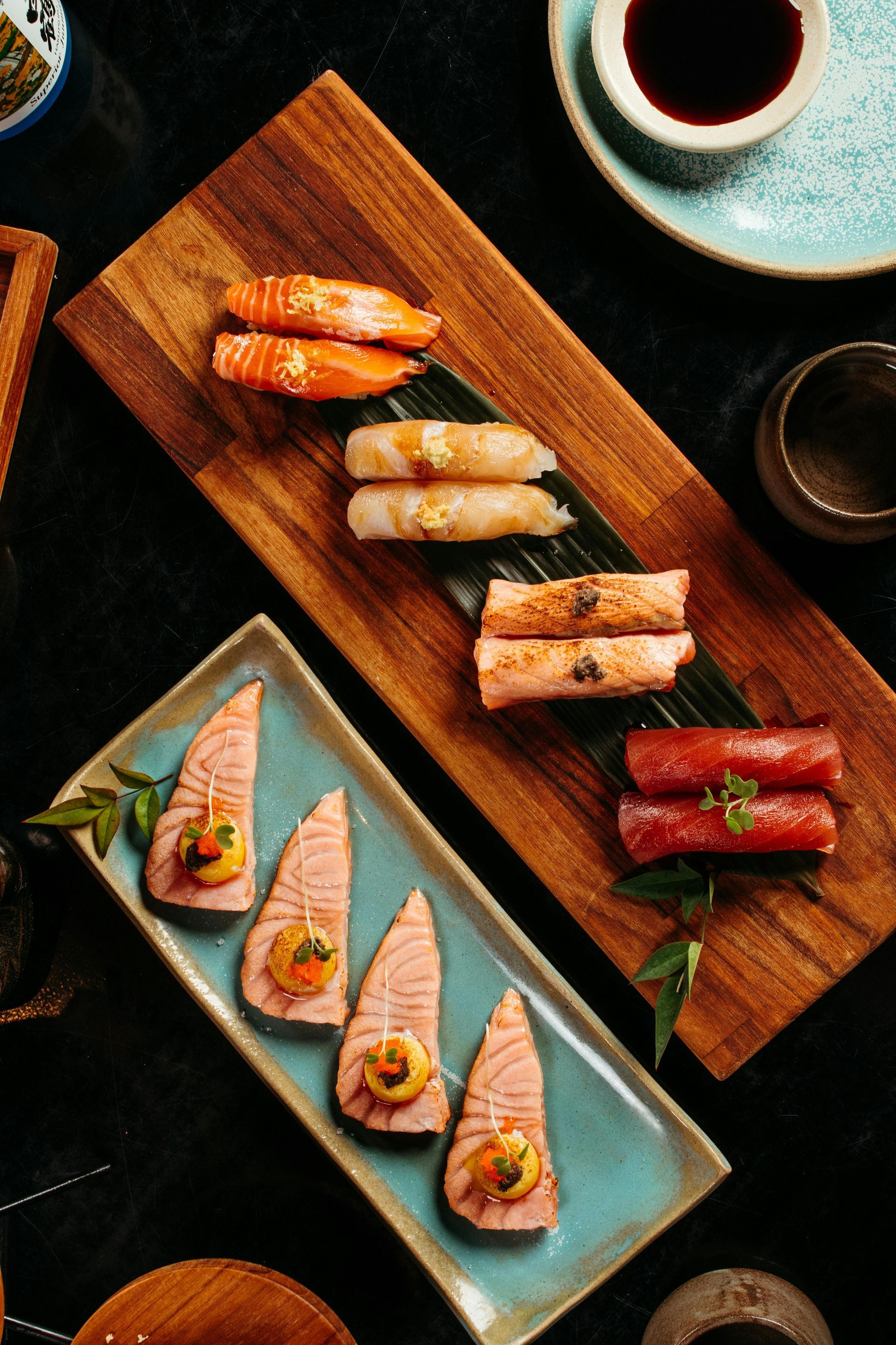Sushi arranged on wooden boards with soy sauce and small bowls.