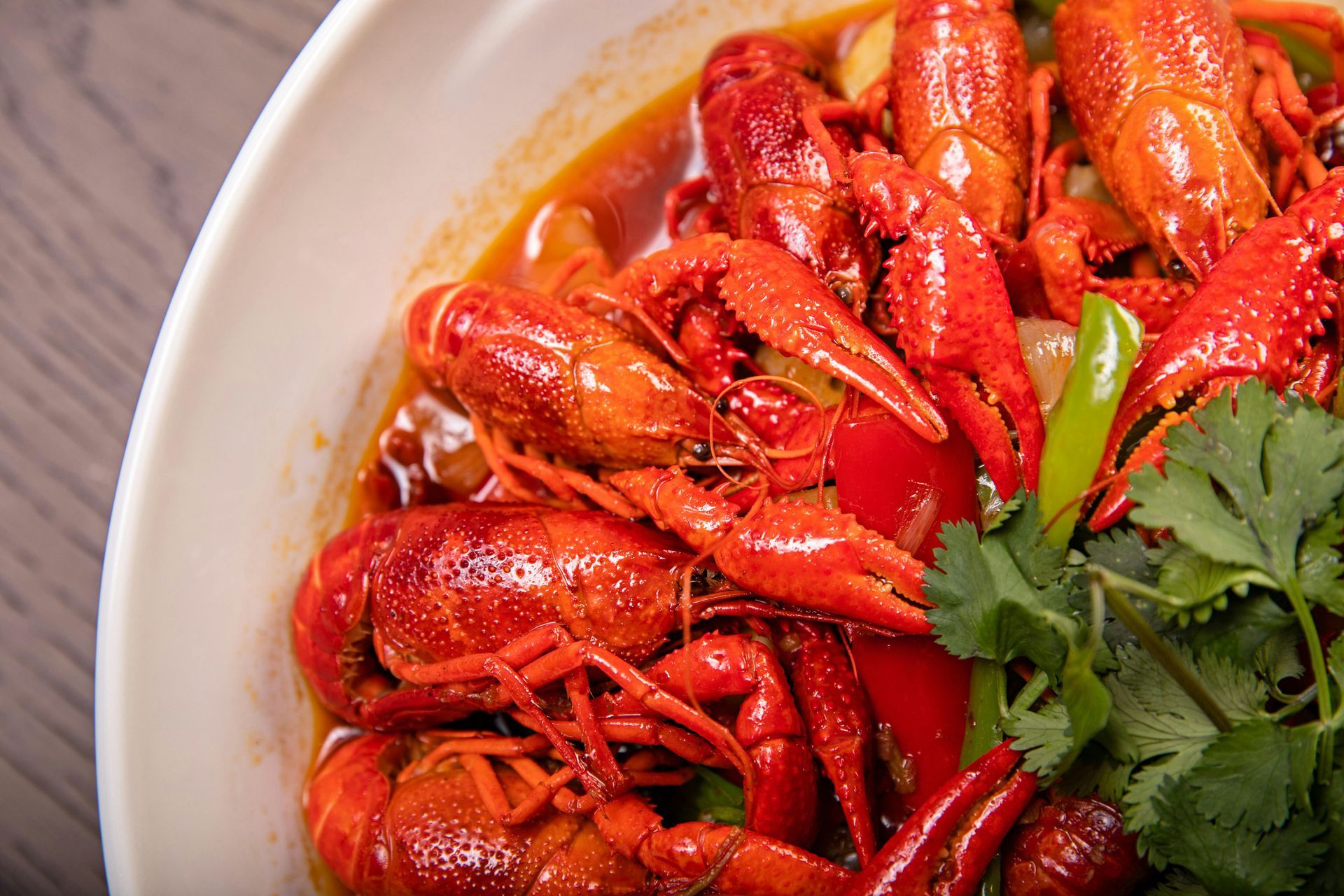 Crawfish in red sauce with vegetables and cilantro in a white bowl.
