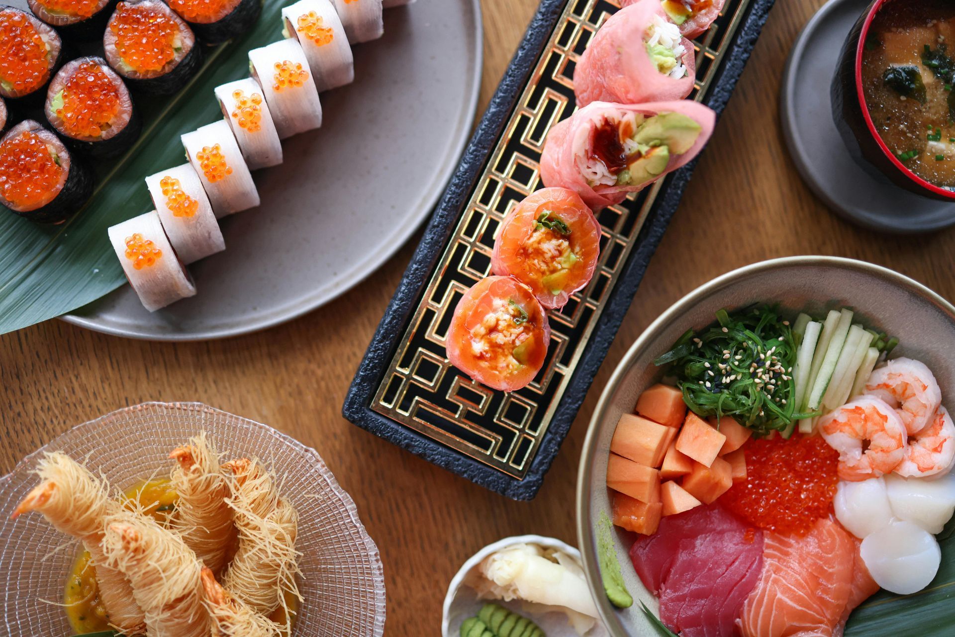 Sushi and sashimi platter with various rolls, shrimp tempura, and miso soup.