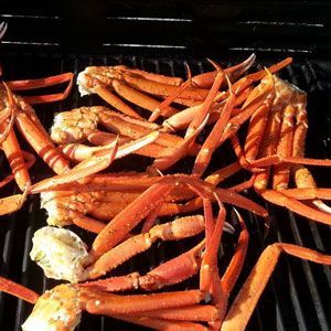 Grilled crab legs on a barbecue grill. Orange and white shell with dark grill lines.